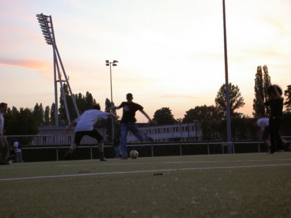 Abendstimmung auf dem Sportplatz. Zwei Menschen spielen Fußball